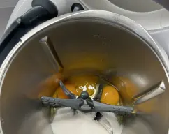 Step <p>Coloque la mariposa en las cuchillas. Añada el huevo, las yemas y el azúcar y bata 4 min/vel 3.5.</p> illustration